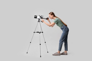 Photo of Young astronomer looking at stars through telescope on grey background