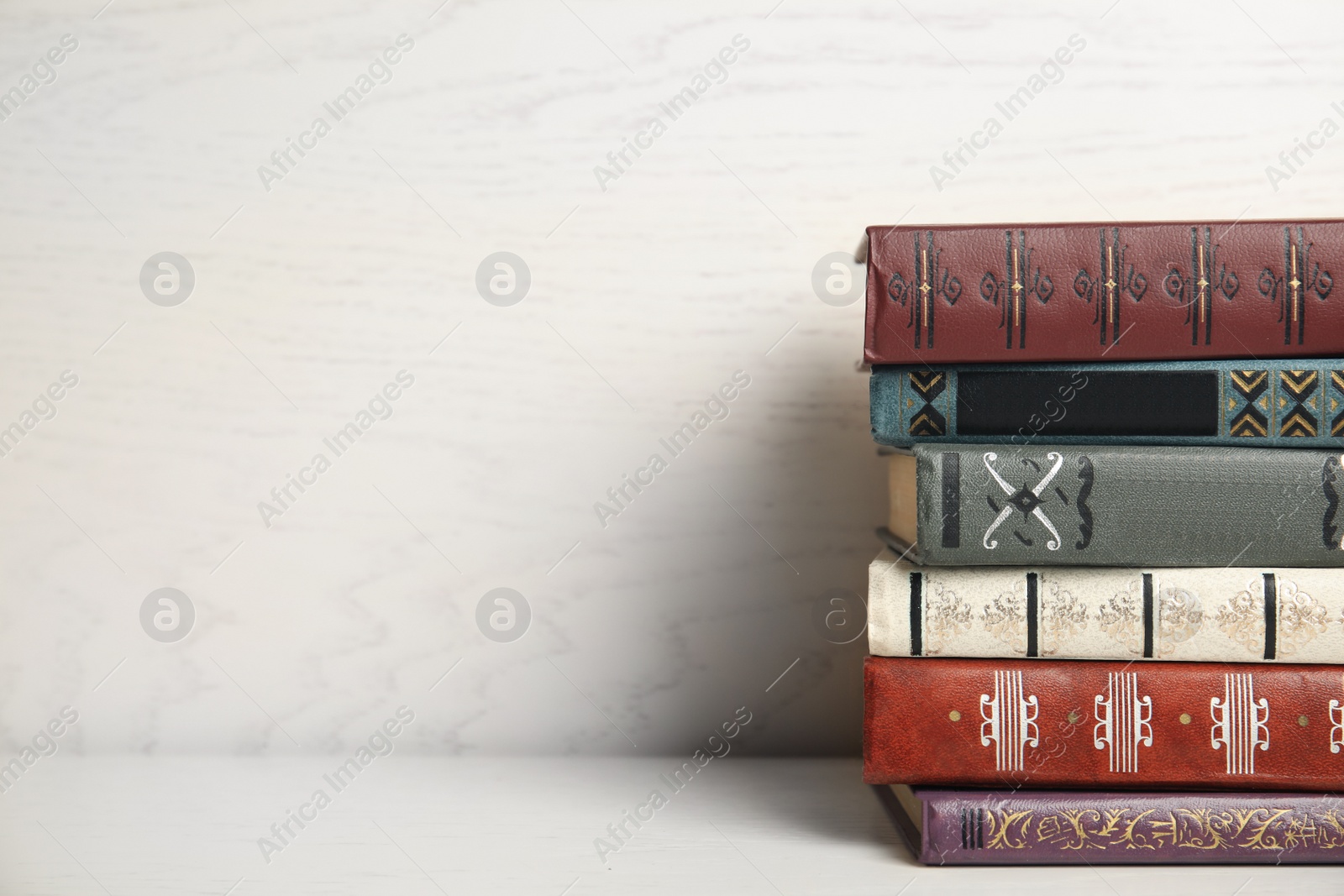 Photo of Collection of different books on table against white wooden background. Space for text