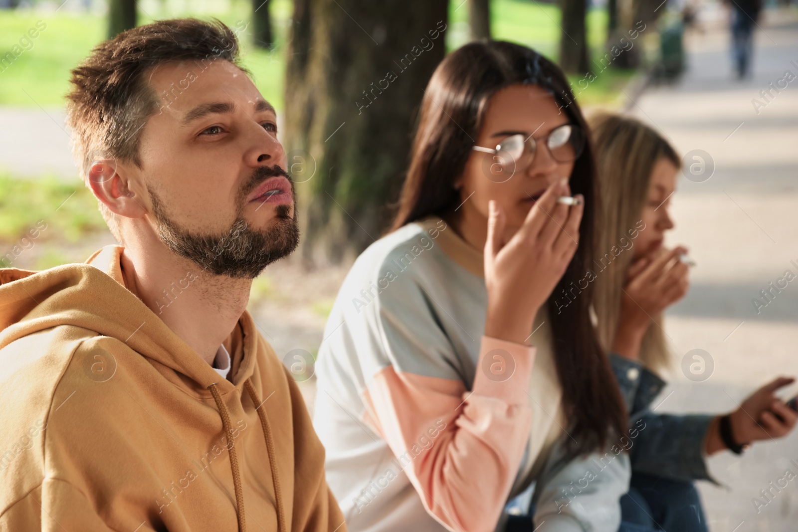 Photo of People smoking cigarettes outdoors on sunny day