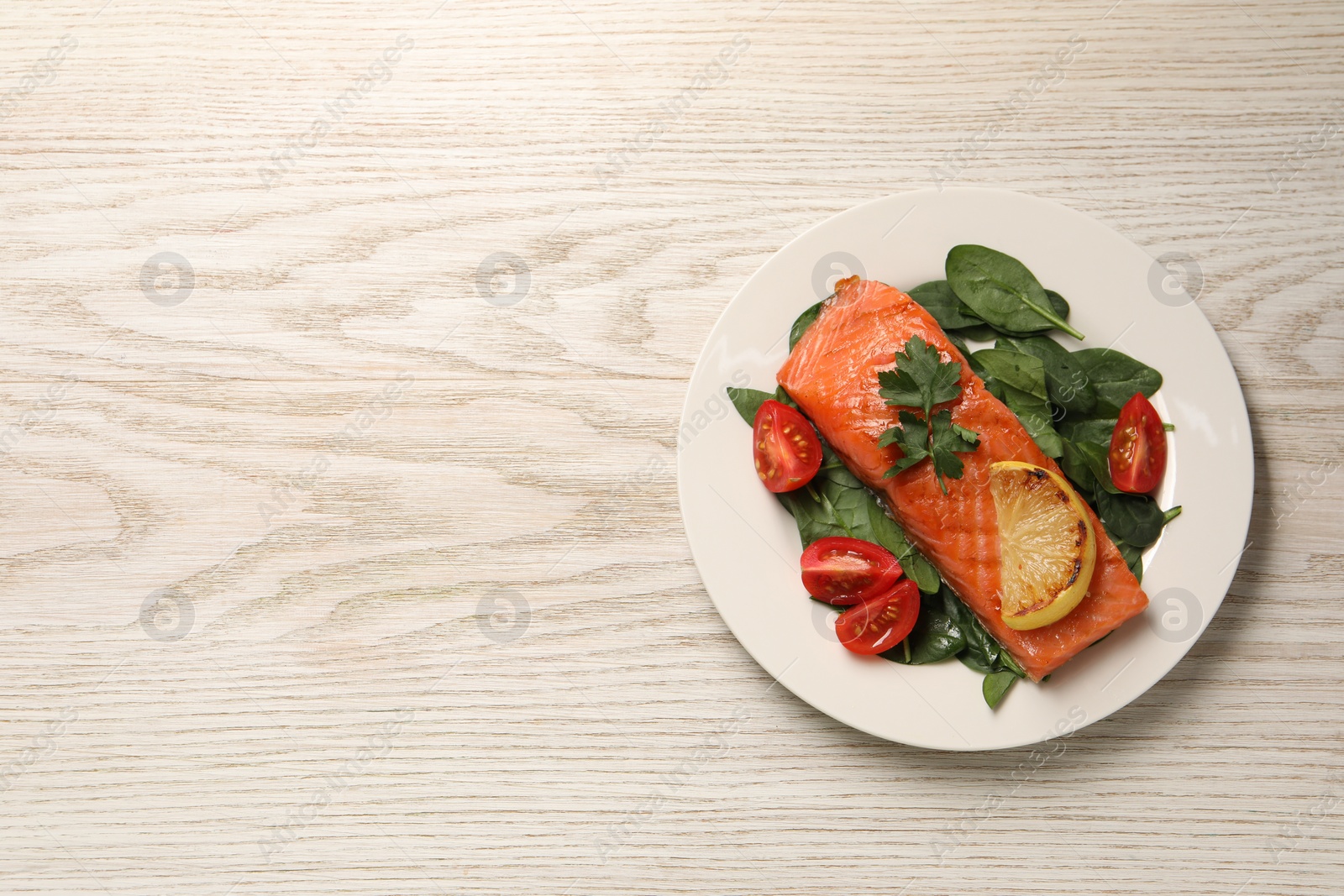 Photo of Tasty grilled salmon with tomatoes, lemon and basil on white wooden table, top view. Space for text