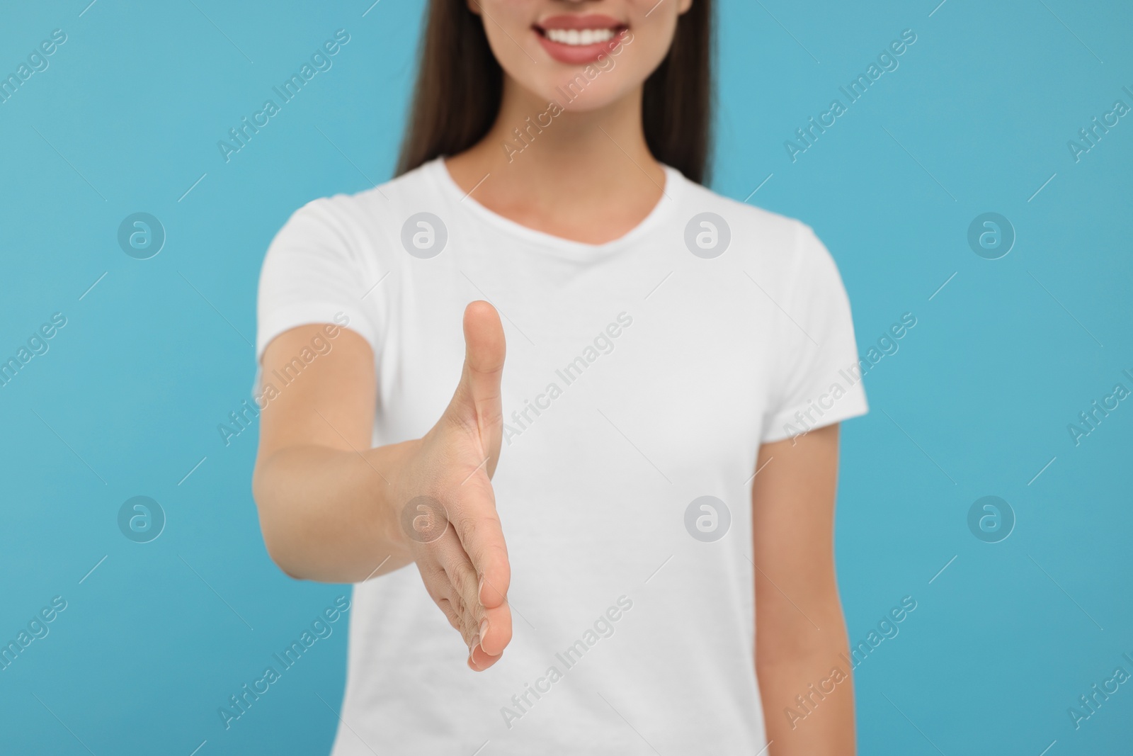 Photo of Woman welcoming and offering handshake on light blue background, closeup