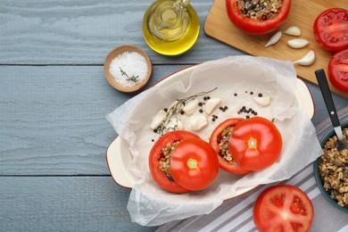 Photo of Uncooked stuffed tomatoes with minced beef, bulgur and mushrooms in baking dish on grey wooden table, flat lay. Space for text