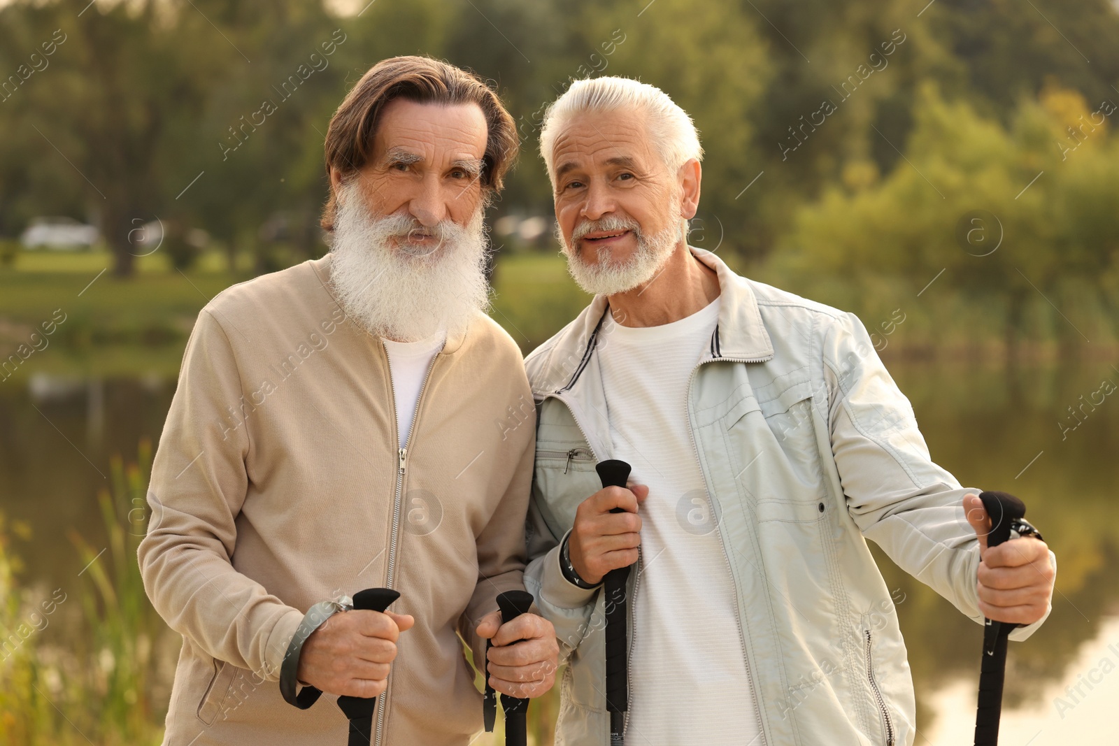 Photo of Two senior men with Nordic walking poles outdoors