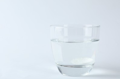 Photo of Glass of water with effervescent tablet on white background, space for text