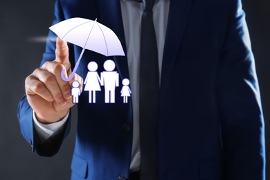 Image of Insurance concept - umbrella demonstrating protection. Man using virtual screen with illustrations, closeup