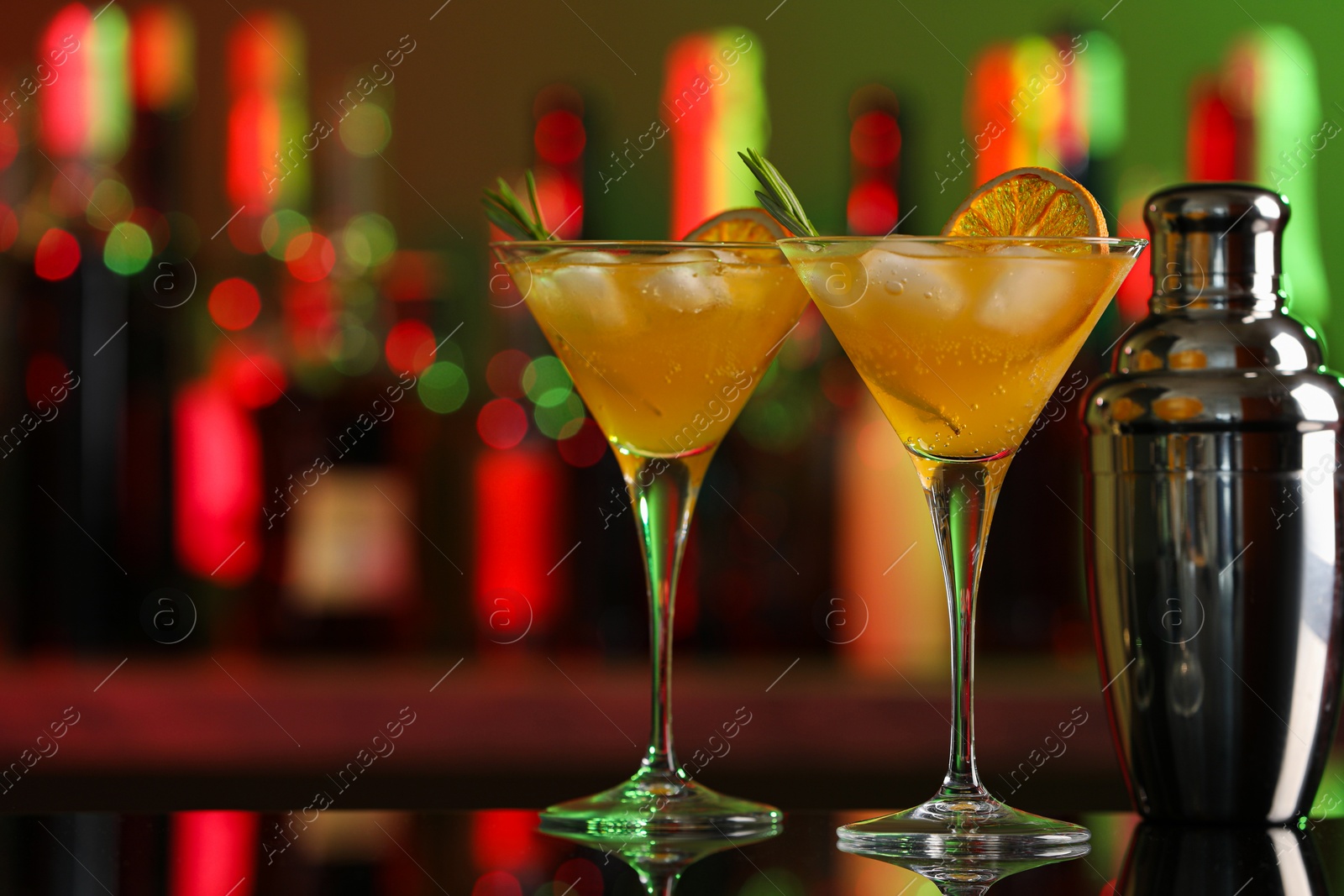 Photo of Martini glasses with cocktail and shaker on counter in bar. Space for text