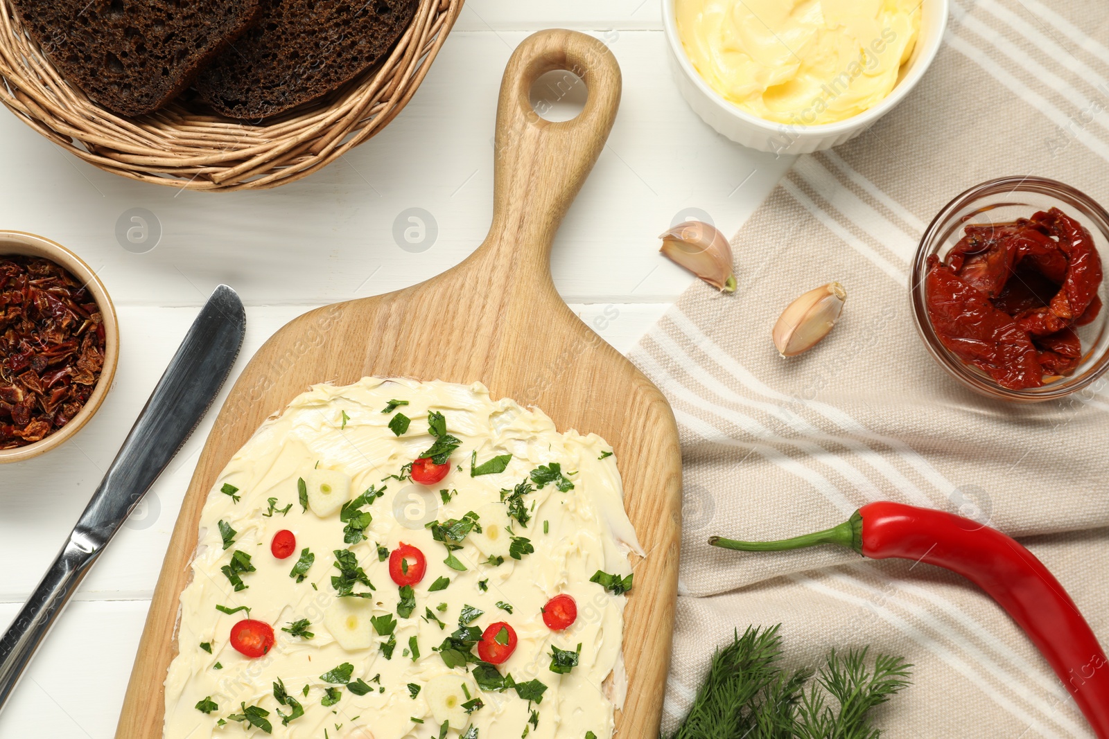 Photo of Fresh natural butter board with ingredients, bread and knife on white wooden table, flat lay