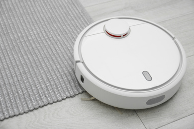 Hoovering floor with modern robotic vacuum cleaner indoors, closeup