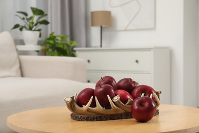 Red apples on wooden coffee table in room, space for text
