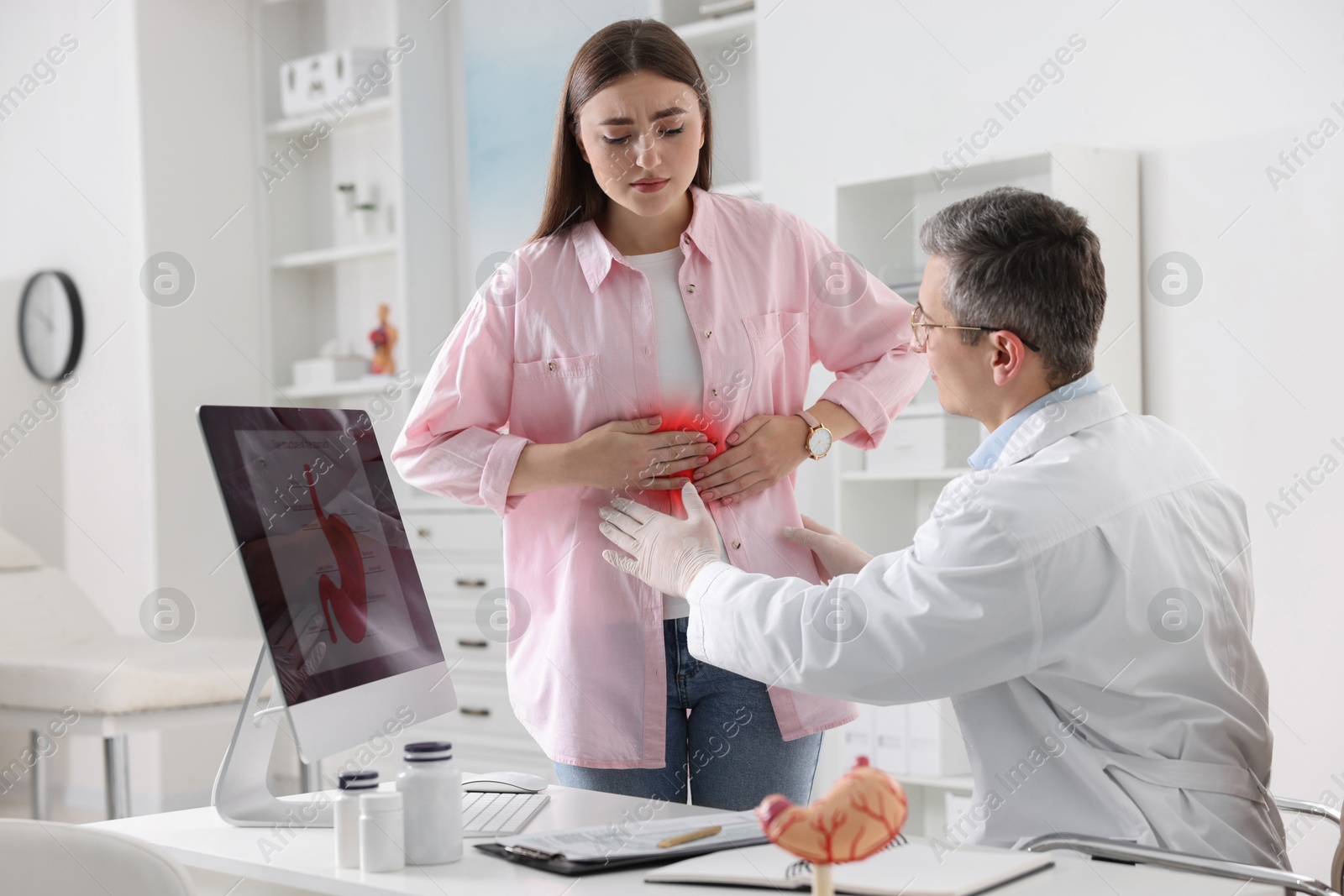 Image of Gastroenterologist examining patient with stomach pain in clinic