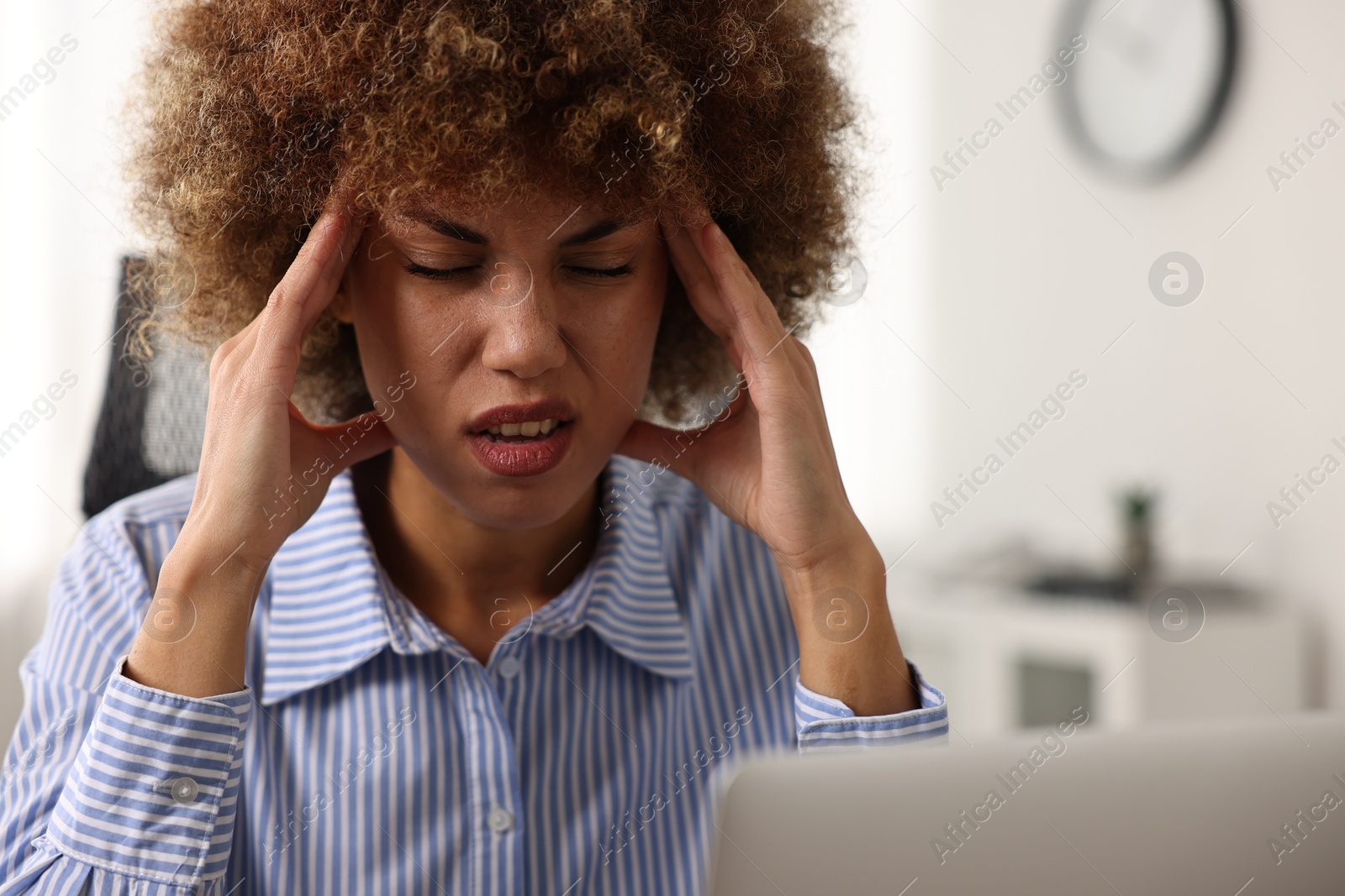 Photo of Woman suffering from headache at workplace in office