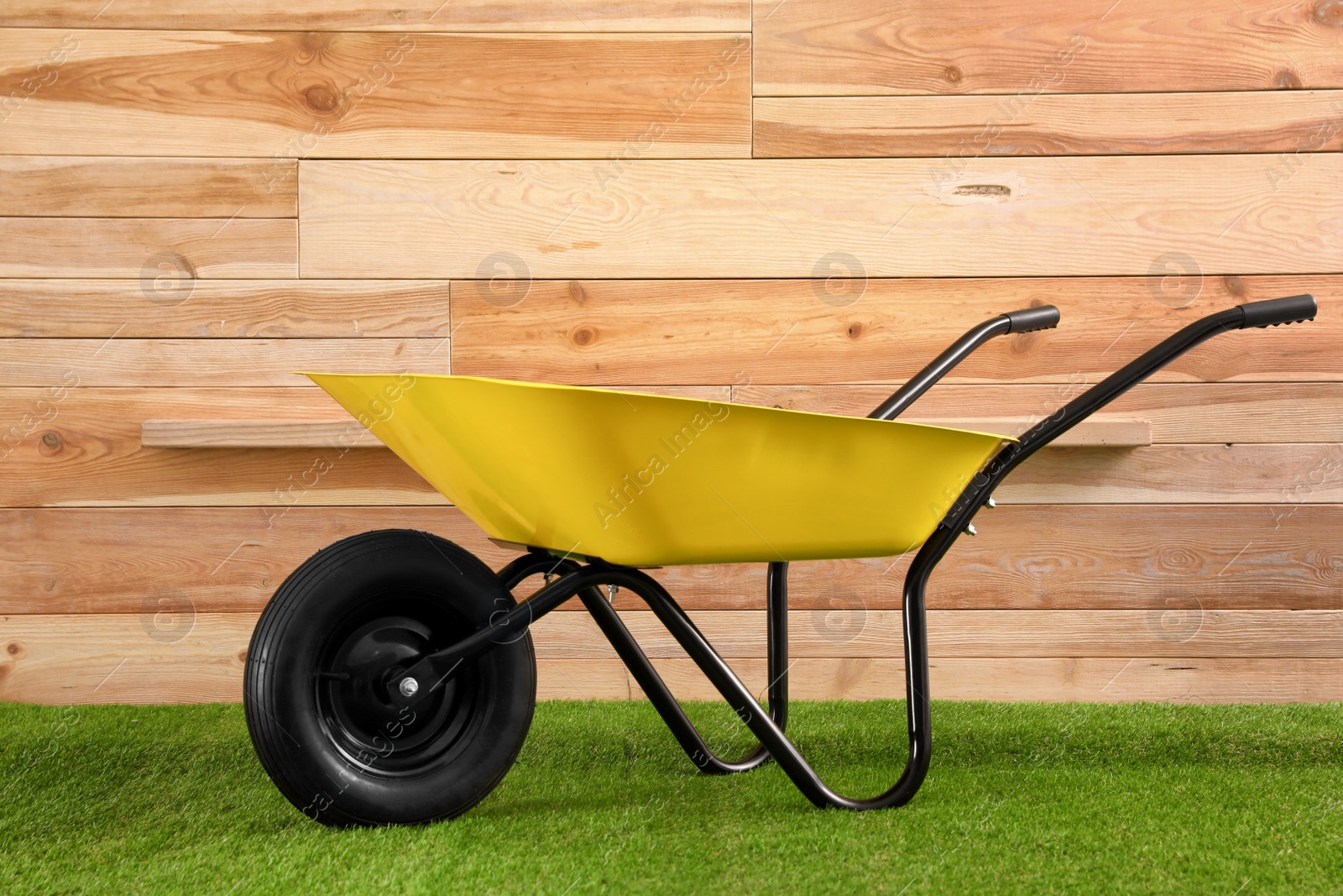 Photo of Color wheelbarrow near wooden wall. Gardening tool
