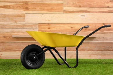 Color wheelbarrow near wooden wall. Gardening tool