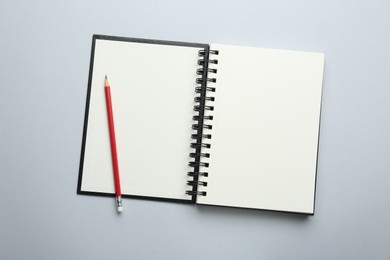 Photo of One notebook and pencil on light grey background, top view. Space for text