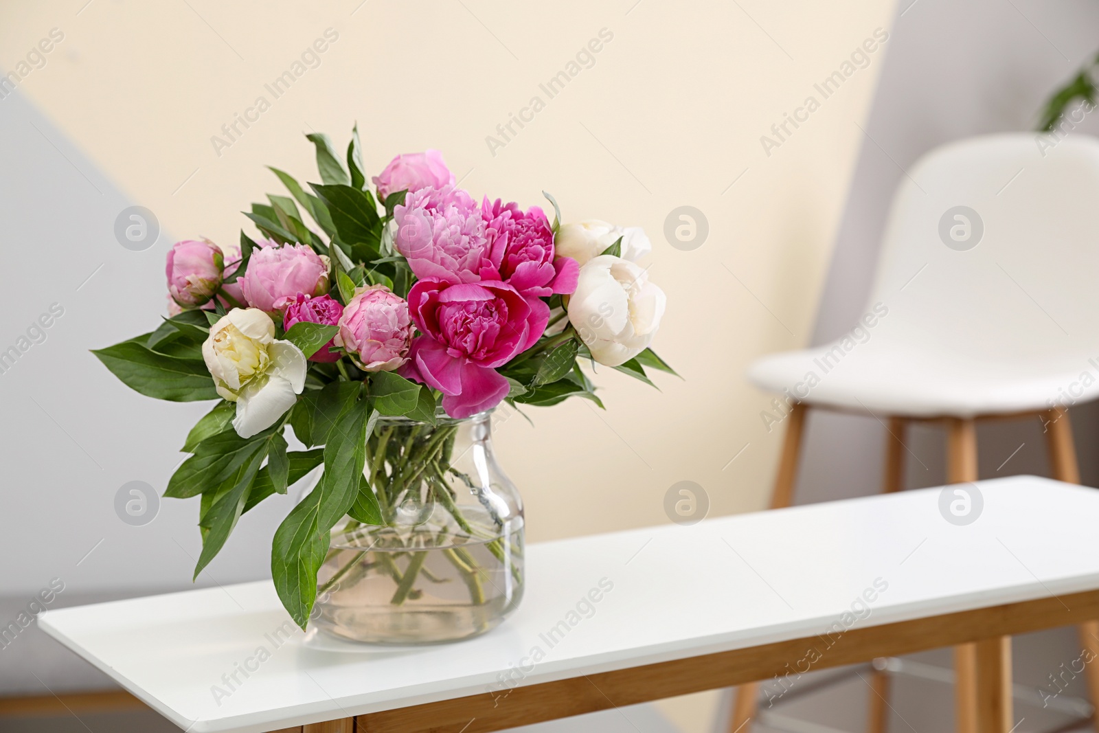 Photo of Vase with bouquet of beautiful peonies on table in room, space for text