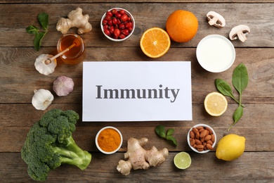 Photo of Card with word Immunity and fresh products on wooden table, flat lay