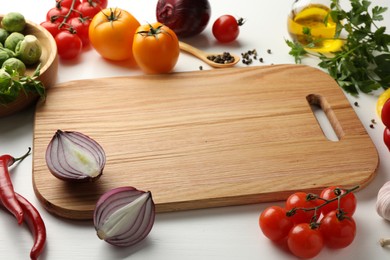 Cutting board with different vegetables on white wooden table, closeup