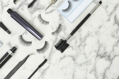 Photo of Flat lay composition with false eyelashes and cosmetic tools on light background