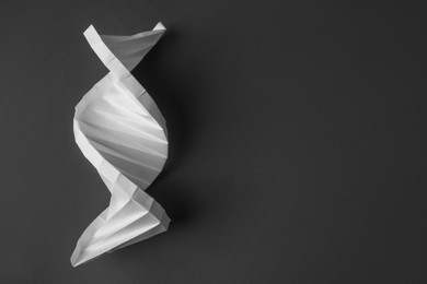 Photo of Paper model of DNA molecular chain on black background, top view. Space for text