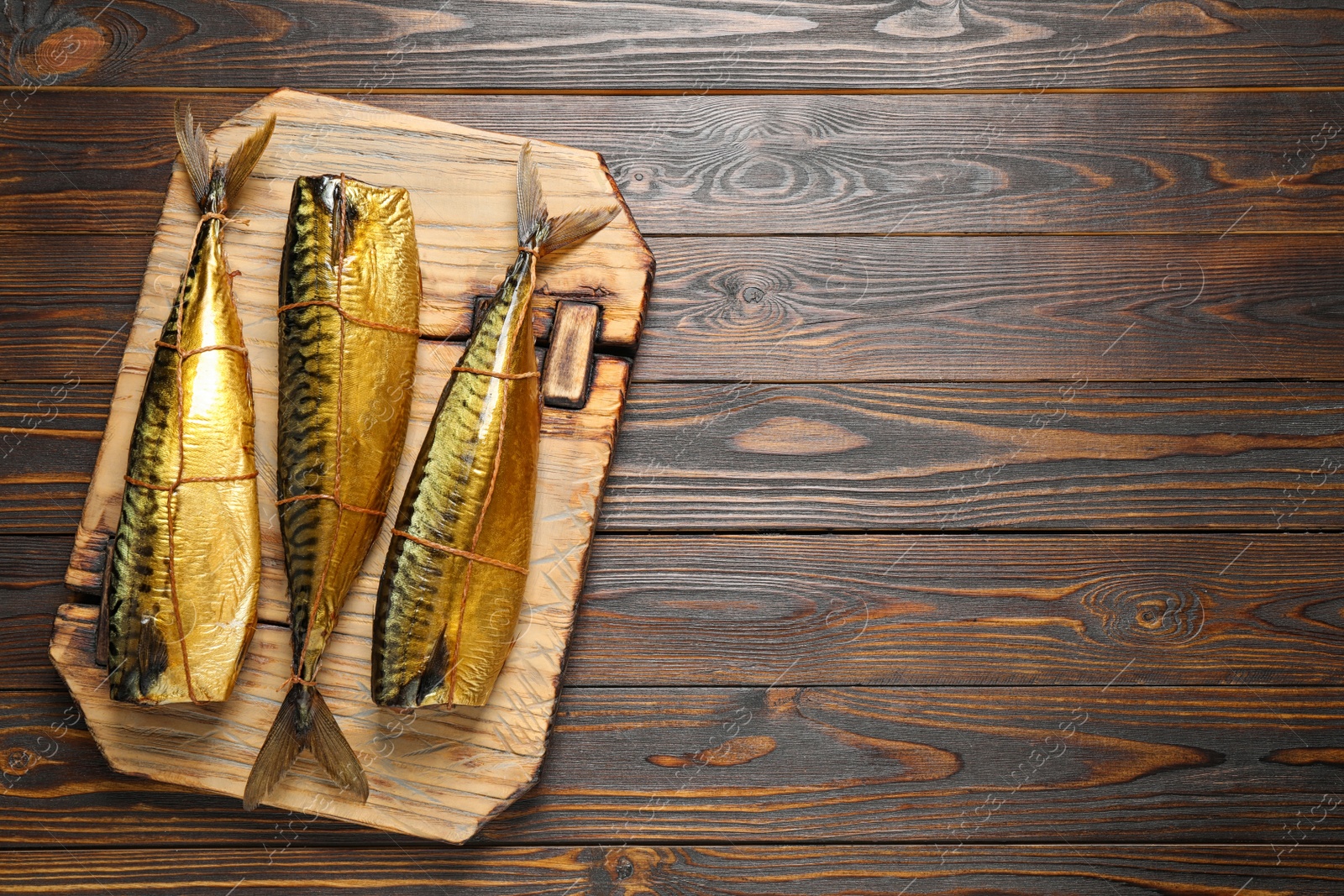 Photo of Tasty smoked fish on wooden table, top view. Space for text