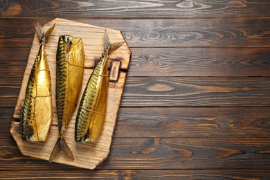 Photo of Tasty smoked fish on wooden table, top view. Space for text