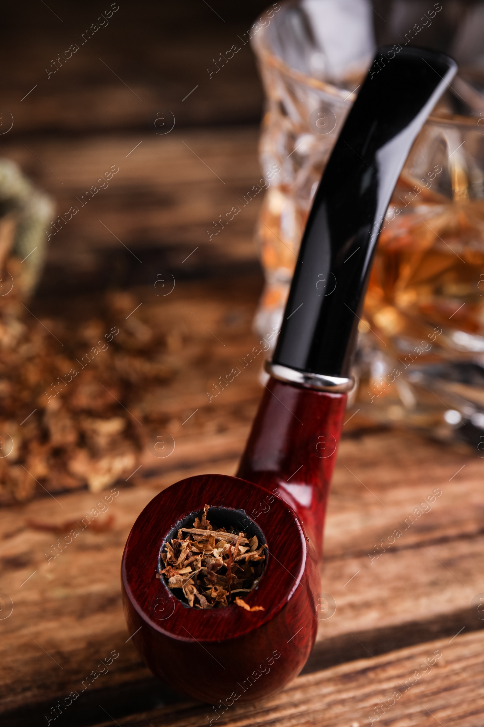 Photo of Smoking pipe with tobacco on wooden table