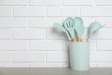 Photo of Holder with kitchen utensils on grey table. Space for text
