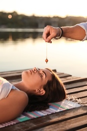Woman at crystal healing session near river outdoors
