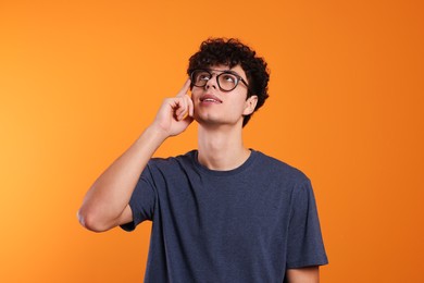 Photo of Portrait of thoughtful young man on orange background