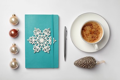 Photo of Turquoise planner, cup of aromatic coffee and Christmas decor on white background, flat lay. New Year aims
