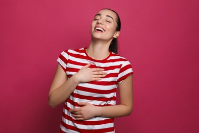 Photo of Beautiful young woman laughing on maroon background. Funny joke