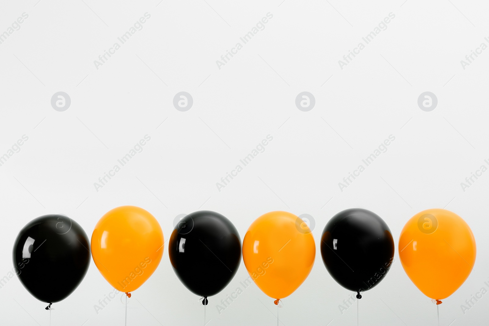 Photo of Colorful balloons on light background, space for text. Halloween party