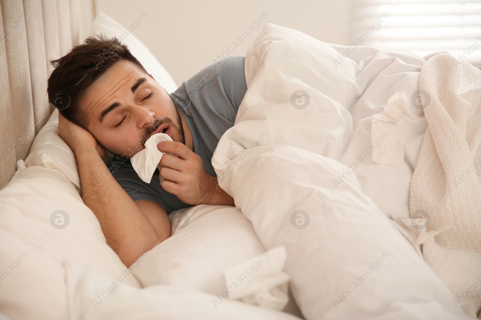 Photo of Sick young man in bed at home. Influenza virus