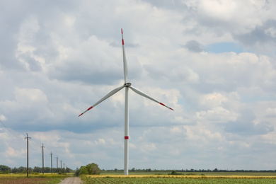 Photo of Modern wind turbine in field on cloudy day. Alternative energy source