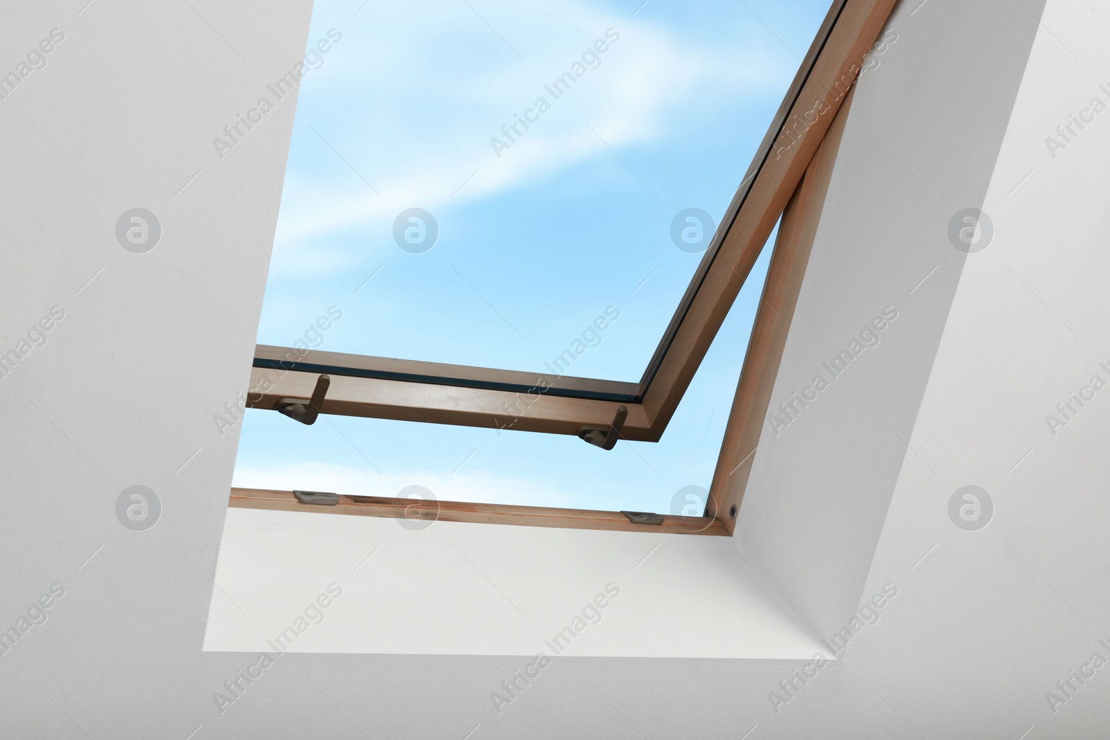 Photo of Open skylight roof window on slanted ceiling in attic room, low angle view