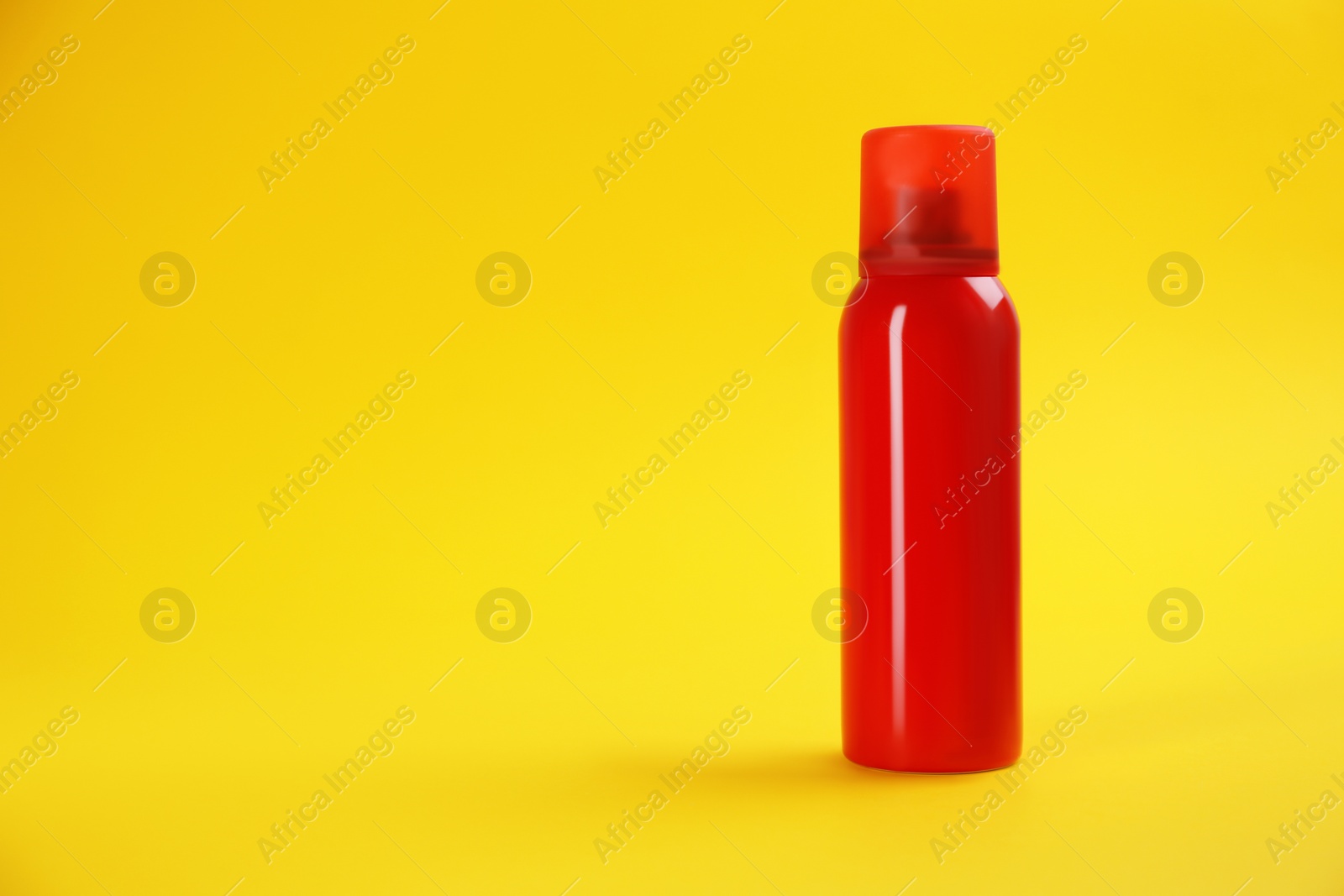 Photo of Bottle with insect repellent spray on yellow background, space for text