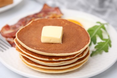 Tasty pancakes served with bacon and arugula on white table, closeup