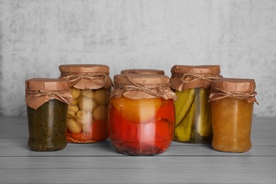 Photo of Many glass jars with different preserved products on wooden table