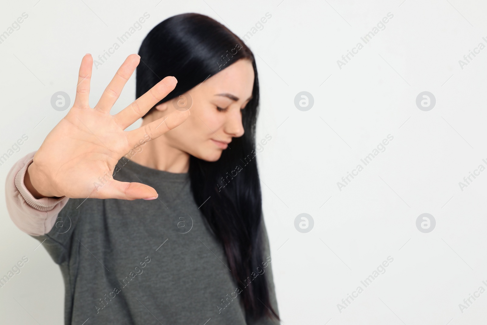 Photo of Young woman making stop gesture against white background, focus on hand. Space for text