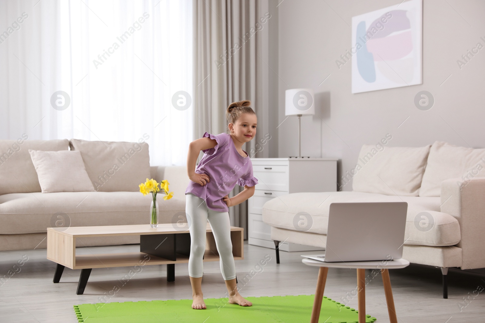 Photo of Cute little girl warming up before online dance class at home