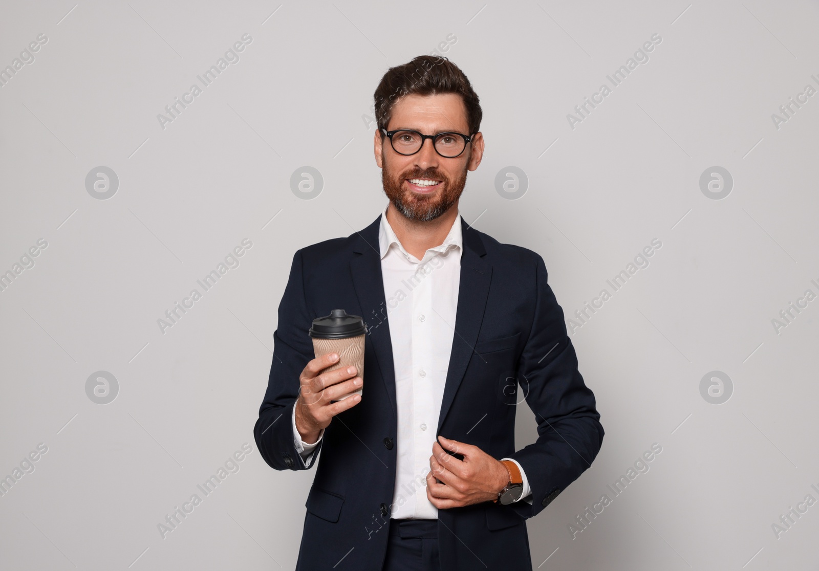 Photo of Smiling bearded man with glasses and paper cup on light grey background