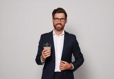 Smiling bearded man with glasses and paper cup on light grey background