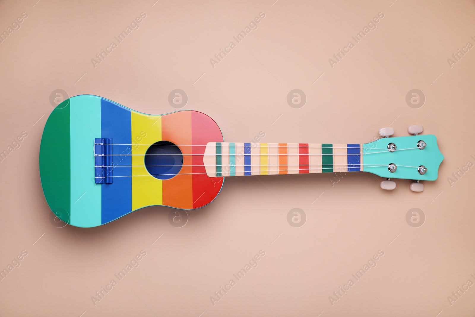 Photo of Colorful ukulele on beige background, top view. String musical instrument