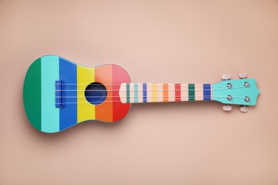 Photo of Colorful ukulele on beige background, top view. String musical instrument