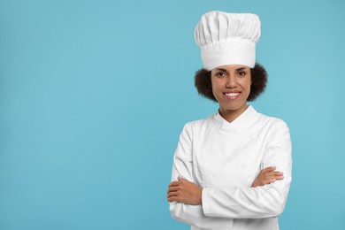 Photo of Portrait of happy female chef in uniform on light blue background. Space for text