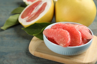 Photo of Peeled pomelo slices on blue wooden table, closeup