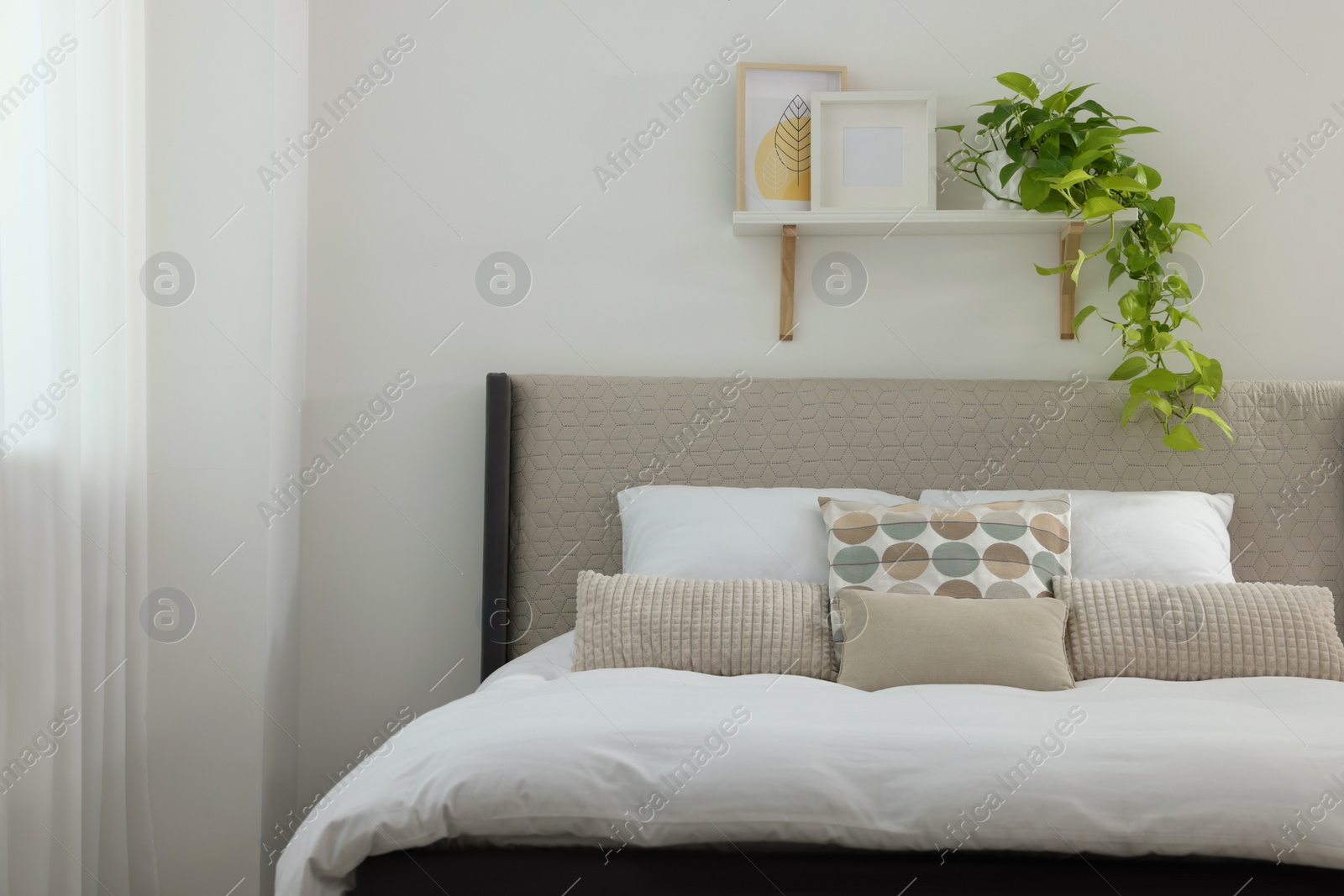 Photo of Stylish bedroom interior with large comfortable bed and shelf