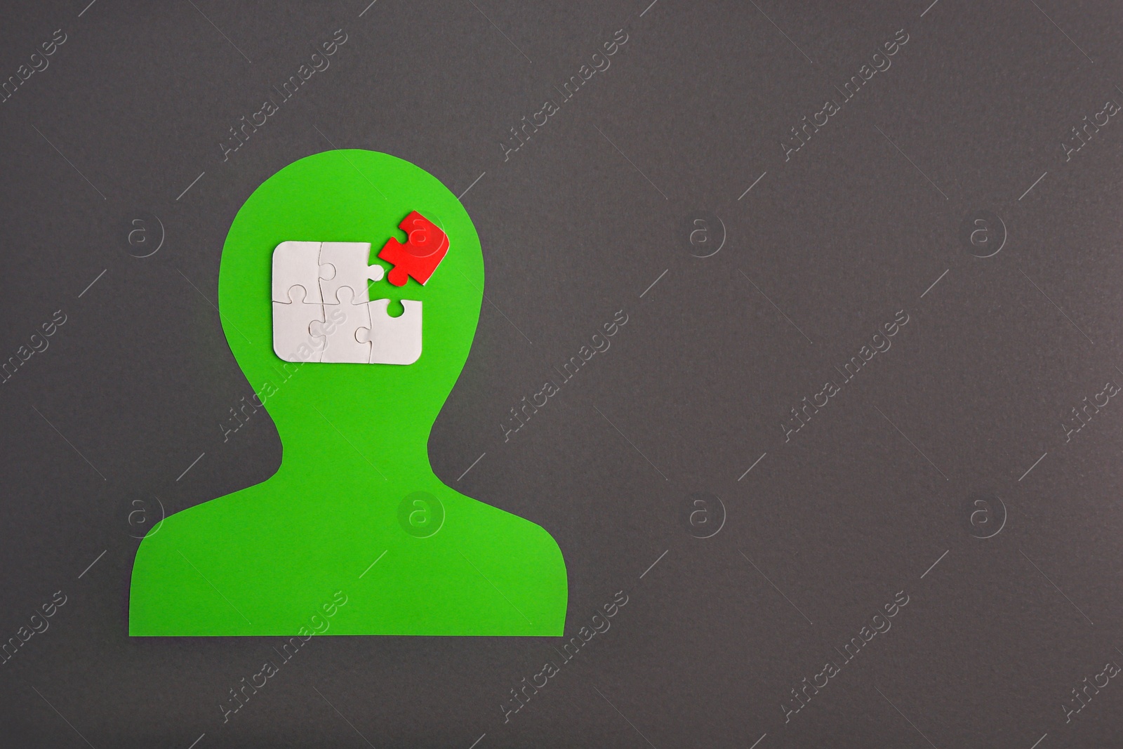 Photo of Human paper cutout with jigsaw puzzles in head, red piece as solution idea on black background, flat lay. Space for text