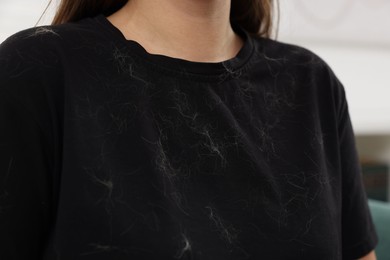 Photo of Woman with pet hair on her black clothers indoors, closeup
