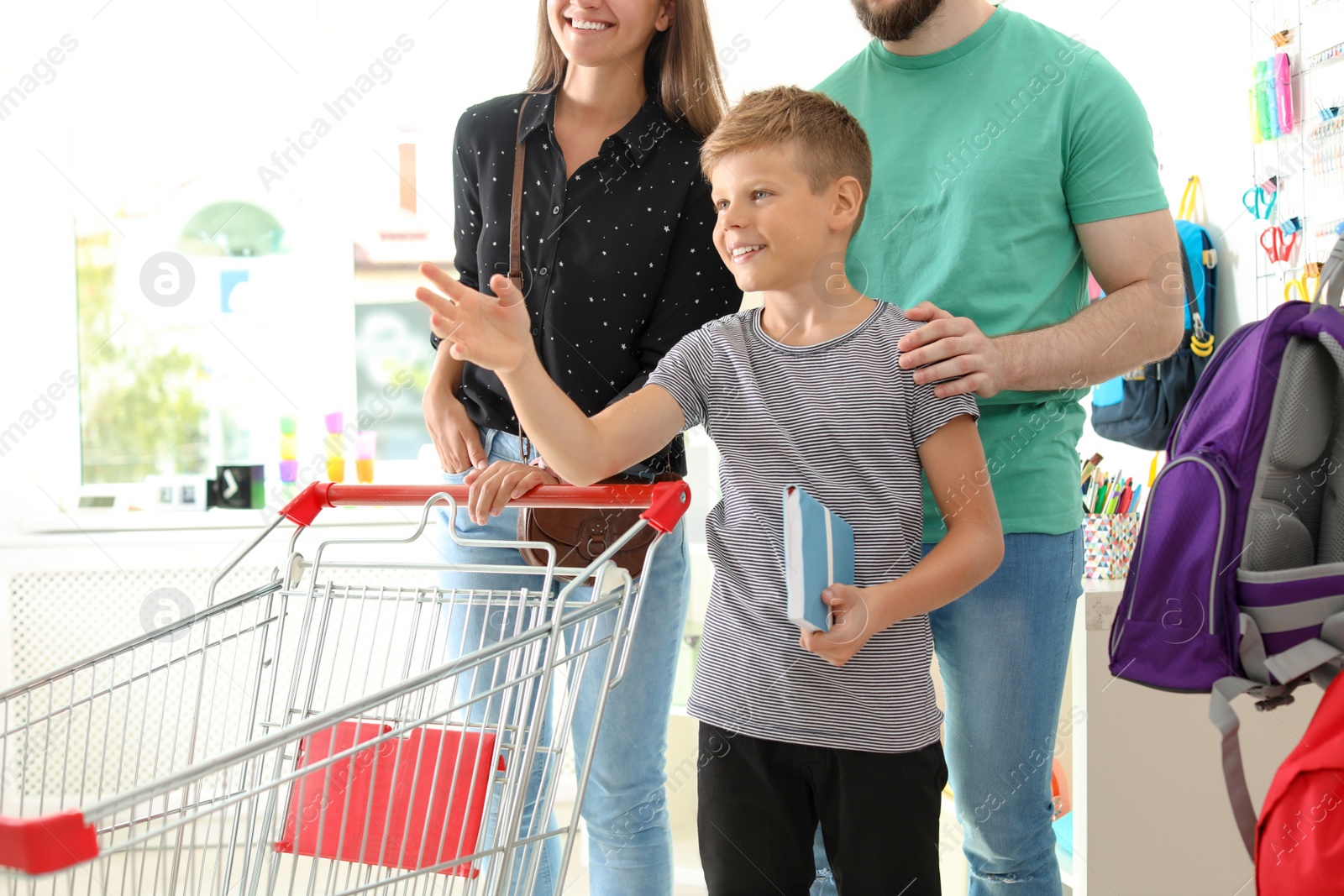 Photo of Little boy choosing school supplies with parents in stationery shop